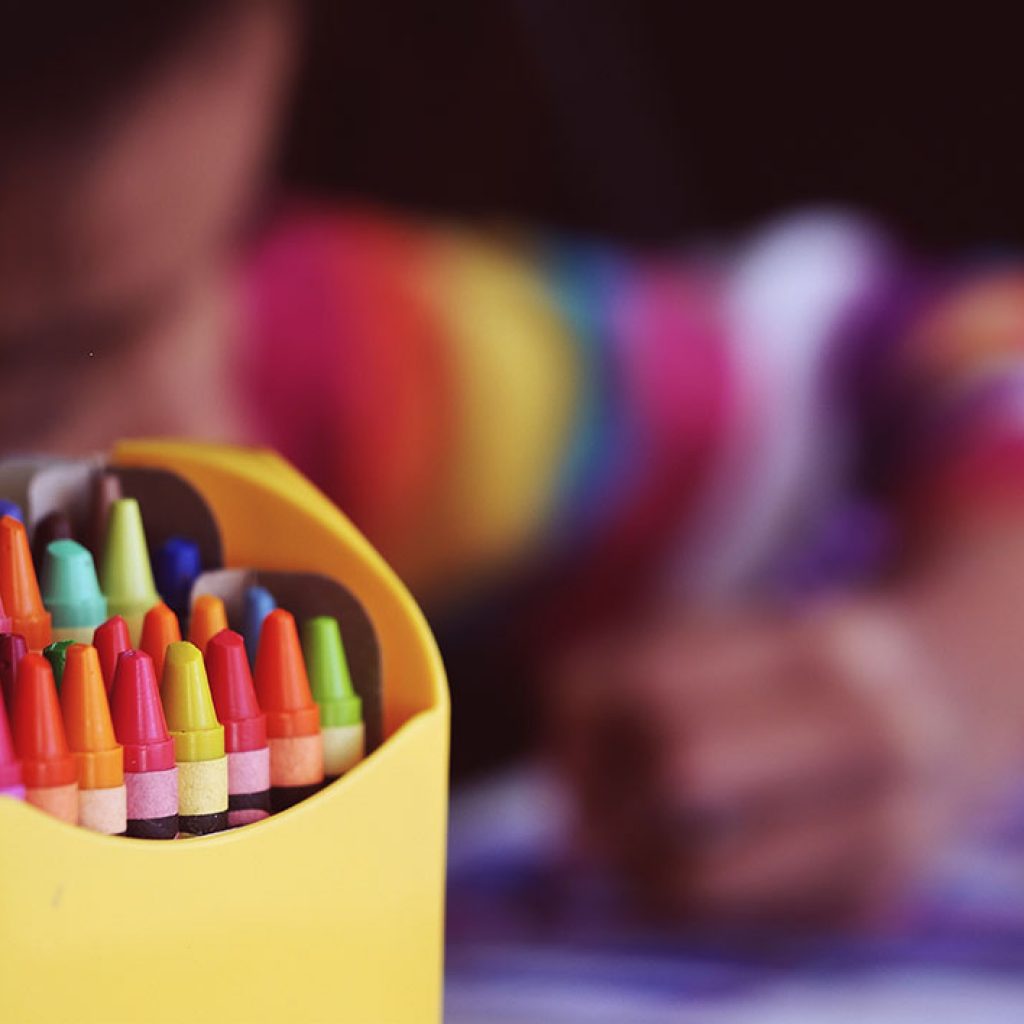 Niño sentado en un escritorio coloreando un papel.