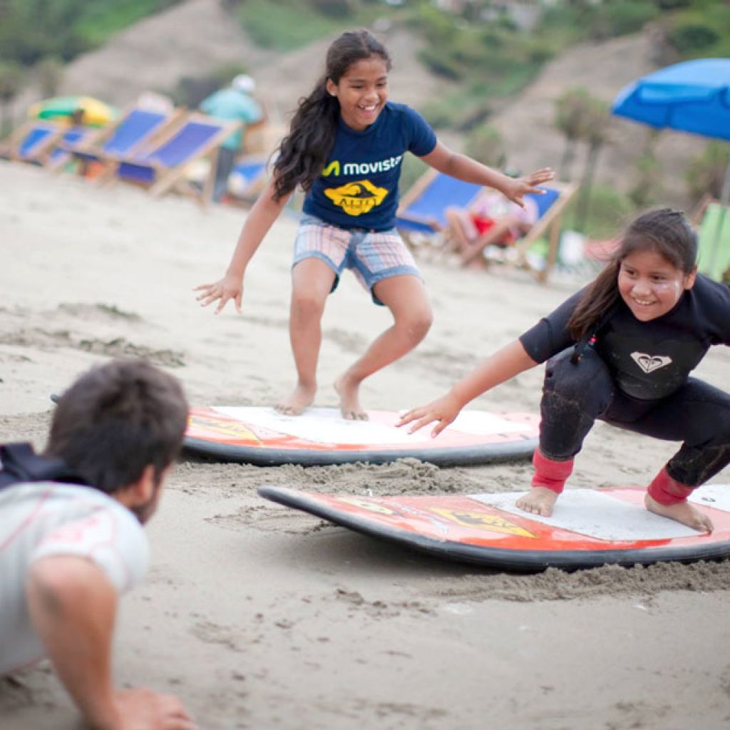 Nenas jugando en la playa de Perú con tablas de windsurf.