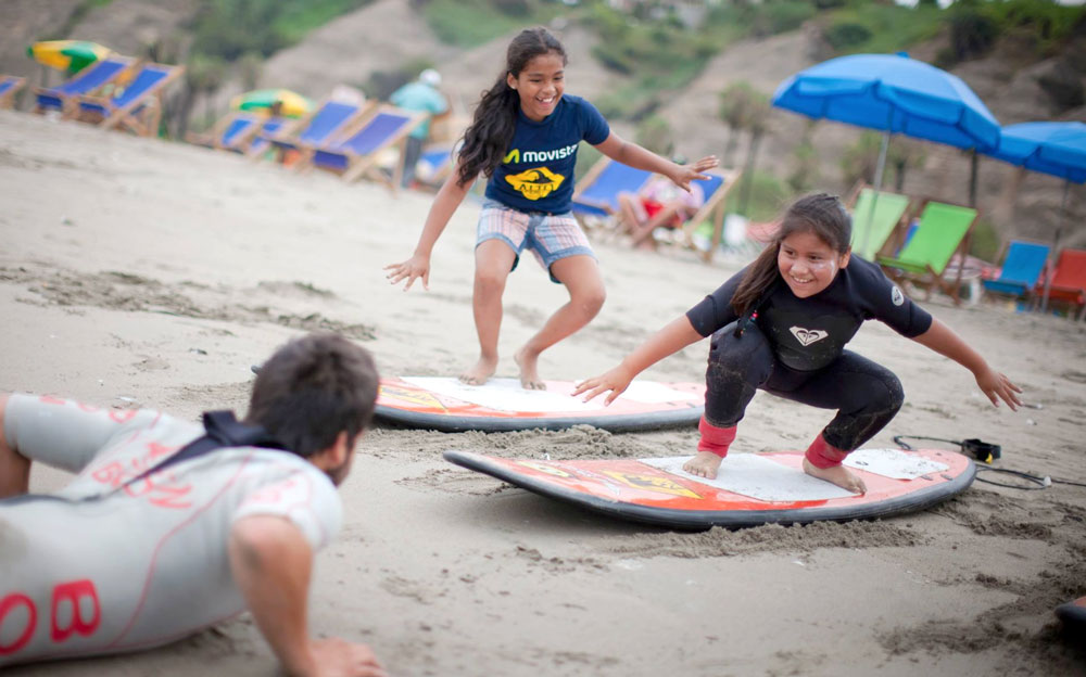 Nenas jugando en la playa de Perú con tablas de windsurf.